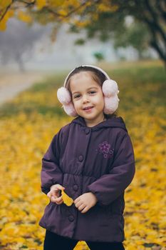 Adorable funny naughty little girl in the park on beautiful autumn day.