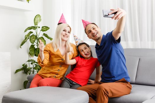 family celebrates birthday online. Mom dad kids at home mobile phone video call self-isolation. Party new technology gadgets. Coronavirus quarantined.