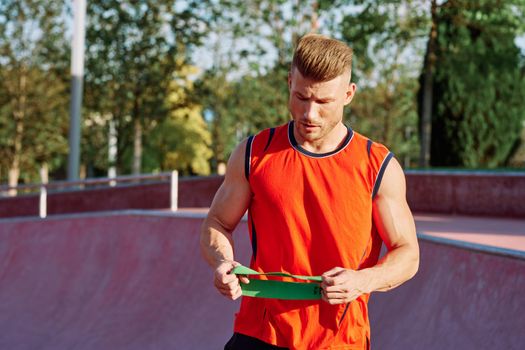 athletic man on the sports ground rubber band exercise. High quality photo