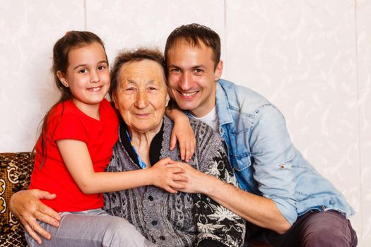 95-year-old woman and her great-granddaughter look at the camera. She is sitting on a chair in her living room.