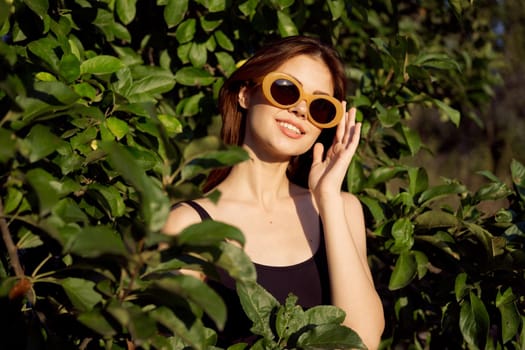 cheerful woman wearing sunglasses green leaves nature summer posing. High quality photo