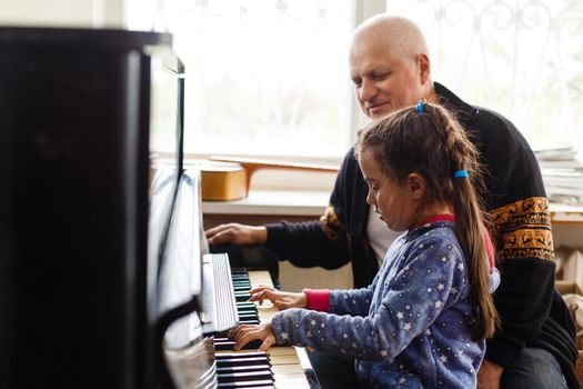 Home lesson on music for the girl on the piano. The idea of activities for the child at home during quarantine. Music concept