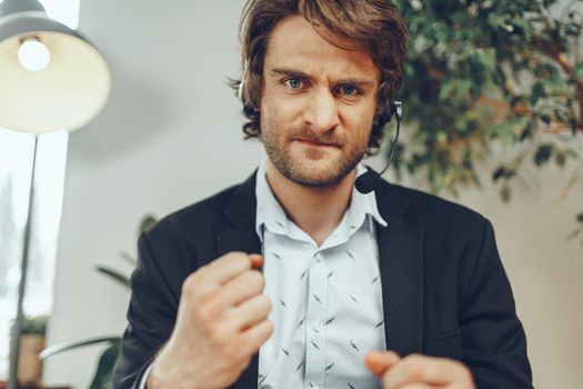 Close up portrait of an angry businessman with headset having stressful annoying online conversation