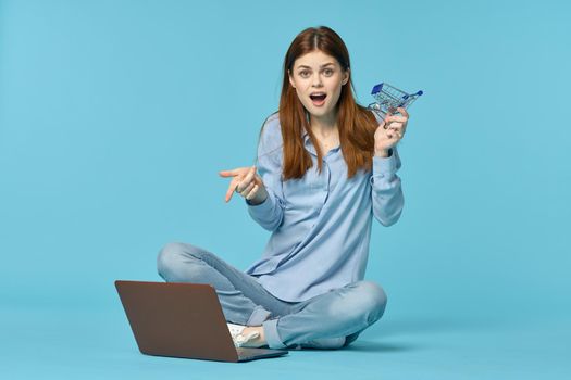 woman with laptop sitting on the floor learning student technology blue background. High quality photo