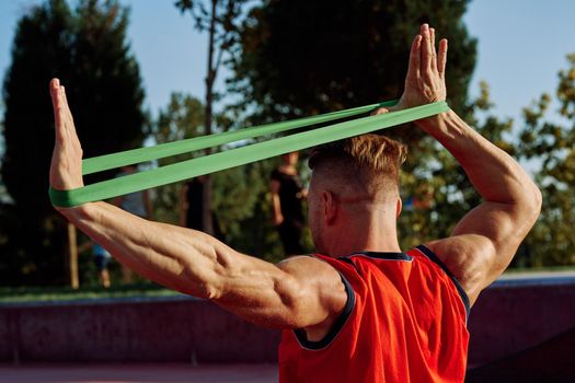 athletic man on the sports ground rubber band exercise. High quality photo