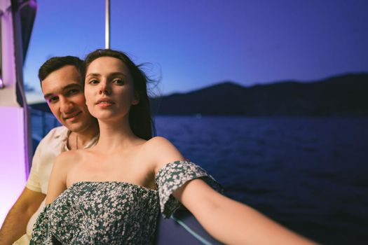 Portrait of happy loving couple on the yacht in the evening