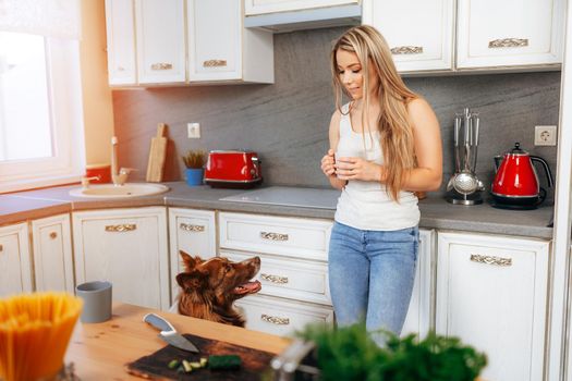 Attractive young woman drinking tea while standing in her kitchen at home