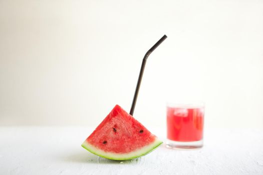 watermelon slice with straw and juice on the white board. Delicious drink - vegetarian cocktail from fresh fruit with ice. conceptual image