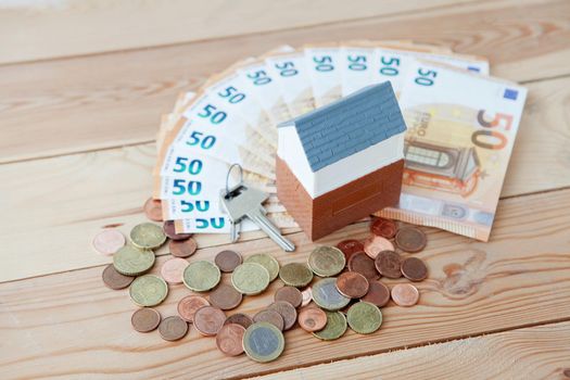 lot of euro money and euro cents near small toy house real estate concept, buying a home or rent a flat