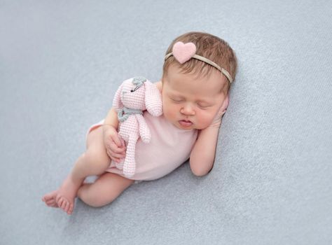 Cute newborn sleeping on side with toy in little hand