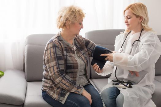 Supportive female nurse visit old grandmother patient at home listen to complains concerns, attentive young woman doctor consulting mature senior grandma, elderly medical healthcare concept