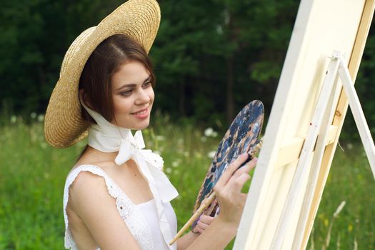 Woman in white dress outdoors artist drawing easel. High quality photo