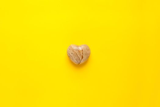 stone heart on a yellow background - top view image of a yellow heart shaped