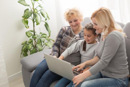 Grandmother and daughter teaching child use laptop application, playing game