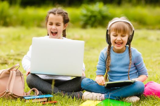 Two beautiful sisters do their homework during quarantine. Children use gadgets for learning. Education, distance learning, home schooling during quarantine