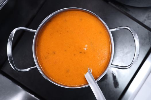 Yellow thick soup in a metal pot on the stove. Style and minimalism in the kitchen design. Top view. Copy space