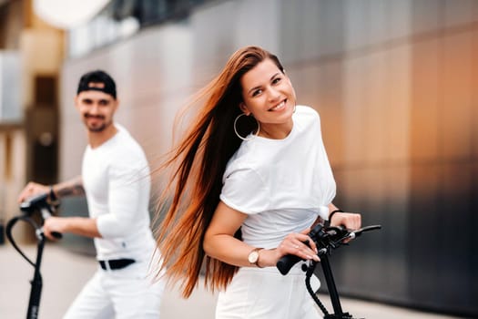 A girl and a guy are walking on electric scooters around the city, a couple in love on scooters