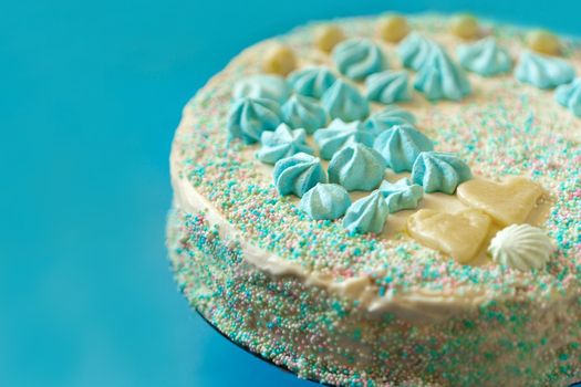 blue cake with candies for babyshower party with meringue close up view. Homemade cake for a newborn boy On a blue background.