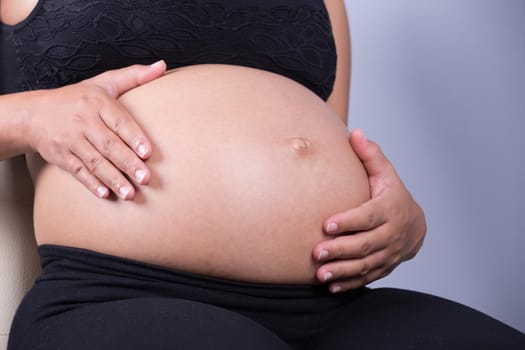 Close-up of pregnant woman belly with her hand on it