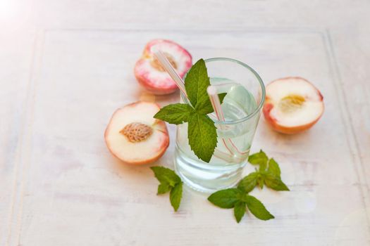 water drink with peaches - refreshing iced tea with peppermint and peaches on grey background, selective focus.