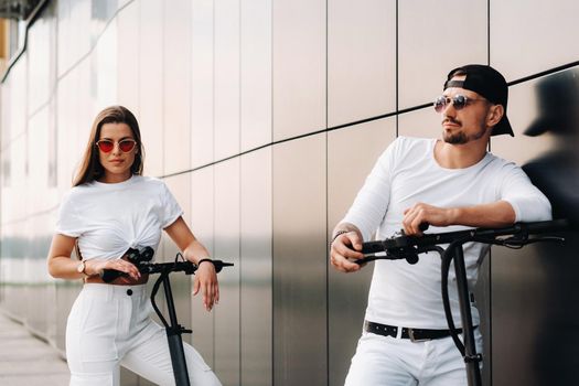 A girl and a guy are walking on electric scooters around the city, a couple in love on scooters