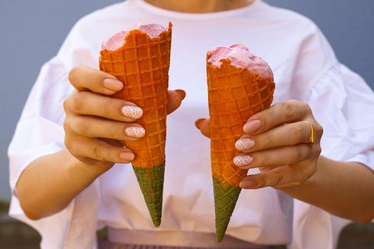 women hand holding rainbow ice cream cone. rainbow ice cream cone - two hands holdling ice cream cones in rainbow colors at hot summer day