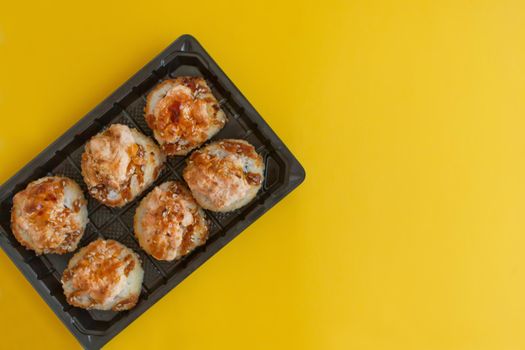 baked sushi set with salmon in plastic packaging on yellow background - bright delicious set of sushi rolls in a plastic box