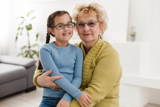 Portrait of happy old grandmother and kid girl looking at camera, smiling grandma with granddaughter making video call, child and granny vloggers recording video blog or vlog together