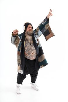 Fat stylish bearded tattoed caucasian man with big belly is posing and dancing wearing ethnic kimono