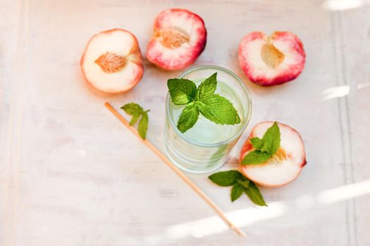 water drink with peaches - refreshing iced tea with peppermint and peaches on grey background, selective focus.