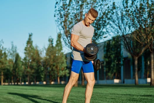 athletic man training with dumbbells in the morning Park. High quality photo