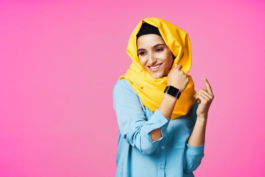 woman wearing yellow hijab electronic watch technology pink background. High quality photo