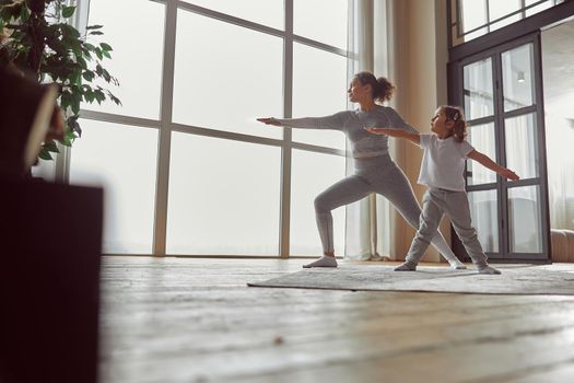 Low angle of calm woman standing in asana while her daughter is repeating after her