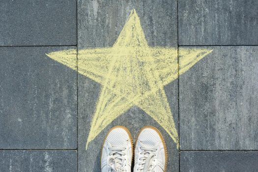 Drawing of crayons on the asphalt - star and feet of woman