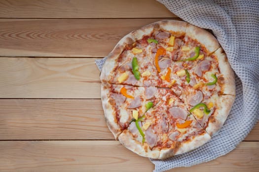 rounded tasty pizza with pepper. Sliced home made delicious pizza on wooden rustic background