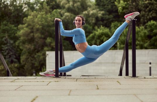 Beautiful fit caucasian woman is doing exercises outdoors at the city