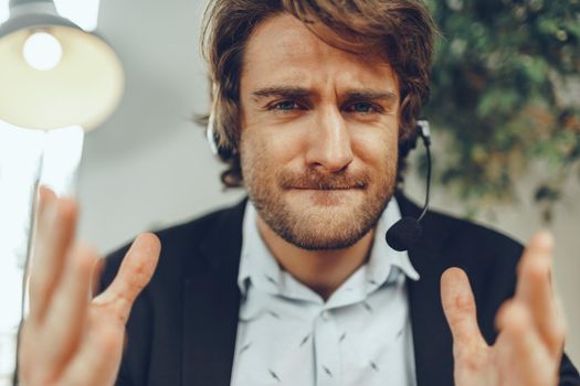 Close up portrait of an angry businessman with headset having stressful annoying online conversation