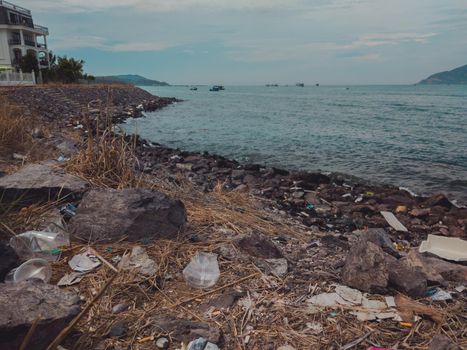 A lot of garbage scattered on the ground, waste near sea on the beach. Problem of of the environment disaster and pollution. Planet ecology. Unauthorized dump of litter outdoors.