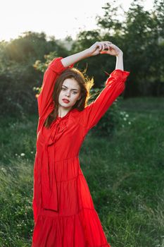 attractive woman in red dress posing in nature green grass. High quality photo