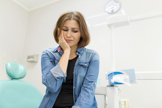 Adult woman sitting in chair of dentist in clinic and preparing for procedure