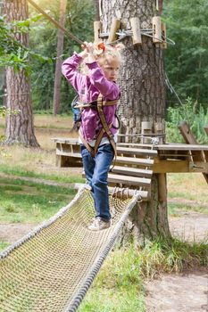 Child girl in adventure climbing high wire park, active lifestyle of children.