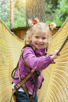 The child girl is 4 years old in adventure climbing high wire park, active lifestyle of children.