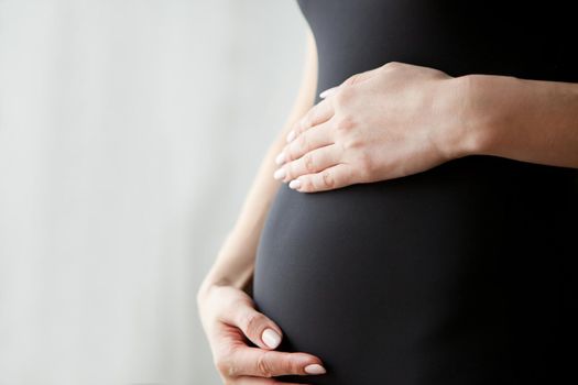 Pregnant woman touching her belly with hands, close up, pregnancy belly