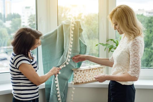 Women choose fabric and accessories for curtains in a new home