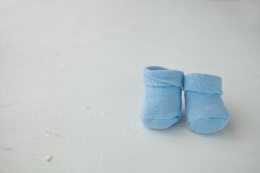 Blue baby socks on a textured rustic background with copy space. Newborn and pregnancy concept. Baby boy socks