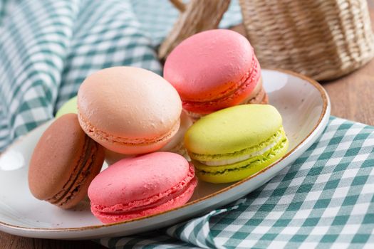 Colorful sweet macaroon cookies on white plate close up