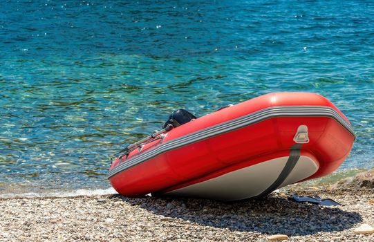 Red rescue inflatable boat, closeup. Empty marine rescue boat. Inflatable boat on the beach it is red in colour with a grey floor and black stripes