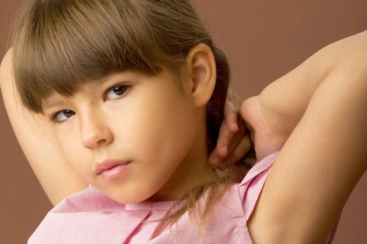 Close up side view portrait of lovely girl. Beautiful child in pink blouse looking forward on brown background with copy space. Lovely dreaming preteen girl posing in studio