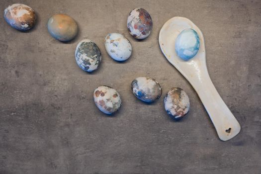 Happy Easter. Series of eggs with marble stone effect painted with natural grey concrete background with large spoon and blank space for text. top view, flat lay