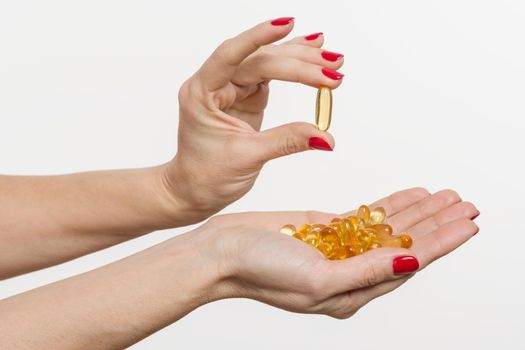 Hand holding capsule of Omega 3 on white background